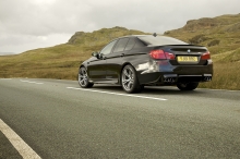 Черный BMW 5 series на дороге с шикарным видом